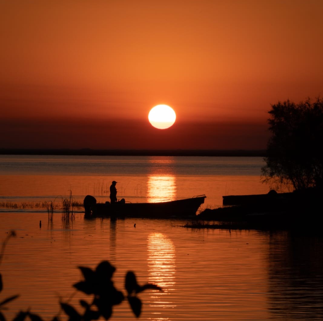 bote en el agua con un atardecer detrás